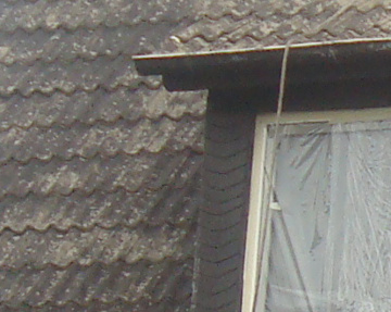 Schlechte Dachbeschichtung - Dachrinne und Schieferplatten beschichtet, abgewaschene Dachpfannen.
